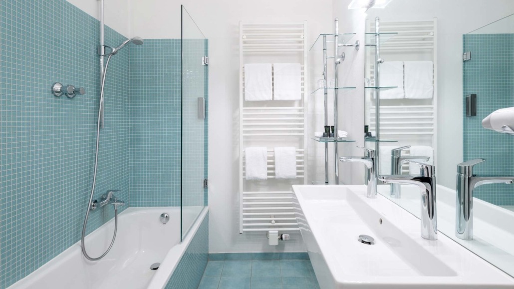 Doppelzimmer - Badezimmer Badezimmer eines Doppelzimmers mit Badewanne, Duschkopf, zwei Waschbecken und Handtüchern an Heizkörper