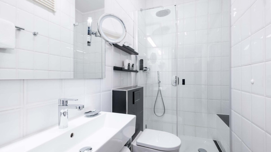 Doppelzimmer - Badezimmer Modernes Badezimmer im Doppelzimmer mit weißer Dusche, Waschbecken, Toilette und Wandregalen