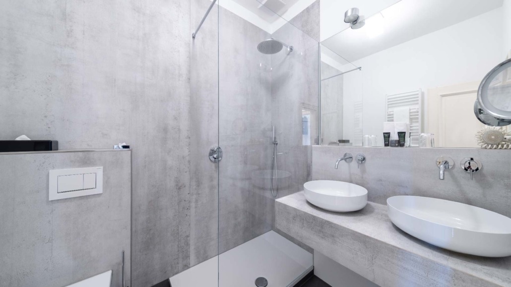 Suite Badezimmer Moderne Suite-Badezimmer mit begehbarer Glasdusche, zwei weißen ovalen Waschbecken auf Betonwaschtisch und wandmontierter Toilette